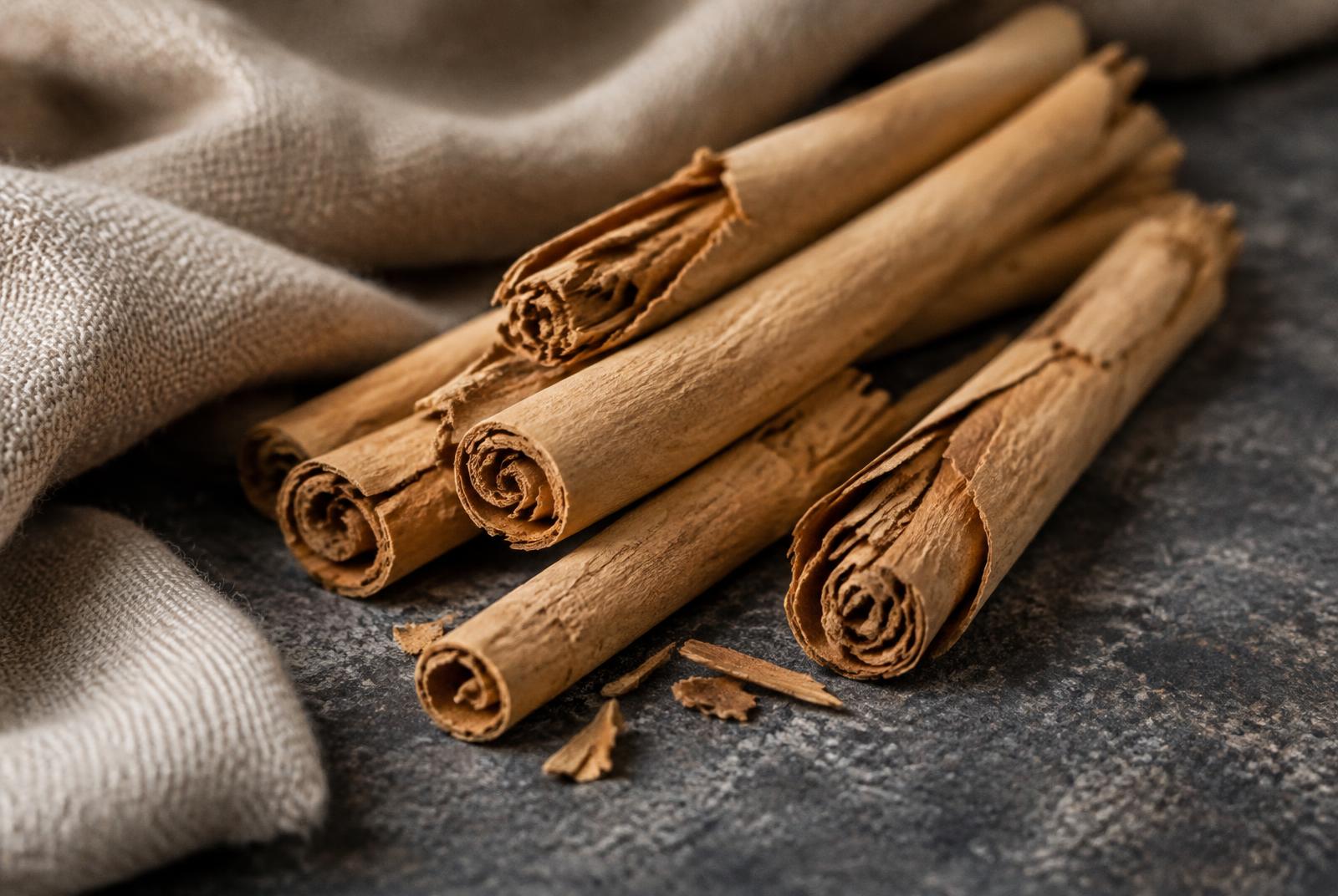 Thin brittle quills of pale tan Ceylon cinnamon bark, some broken to show their many fine rolled layers.